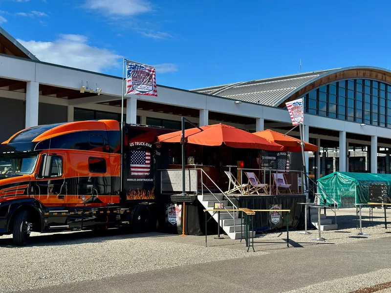 Der Showtruck mit orangefarbenen Sonnenschirmen vor der Messe Friedrichshafen