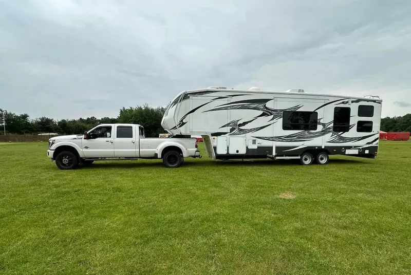Amerikanisches Wohnmobil mit Pick-up davor auf der Wiese