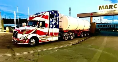 Truck mit Stars-and-Stripes-Lackierung und Tankauflieger bei Nacht
