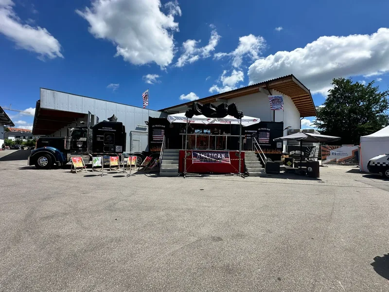 Showtruck mit Sonnenschirmen und Bartischen vor einer Halle