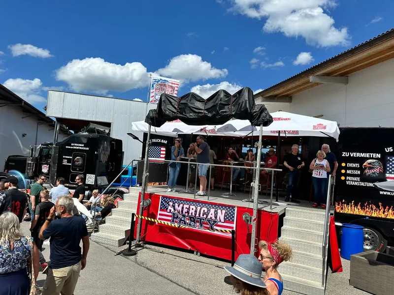 Besucherinnen und Besucher an der roten Theke der US Truck-Bar