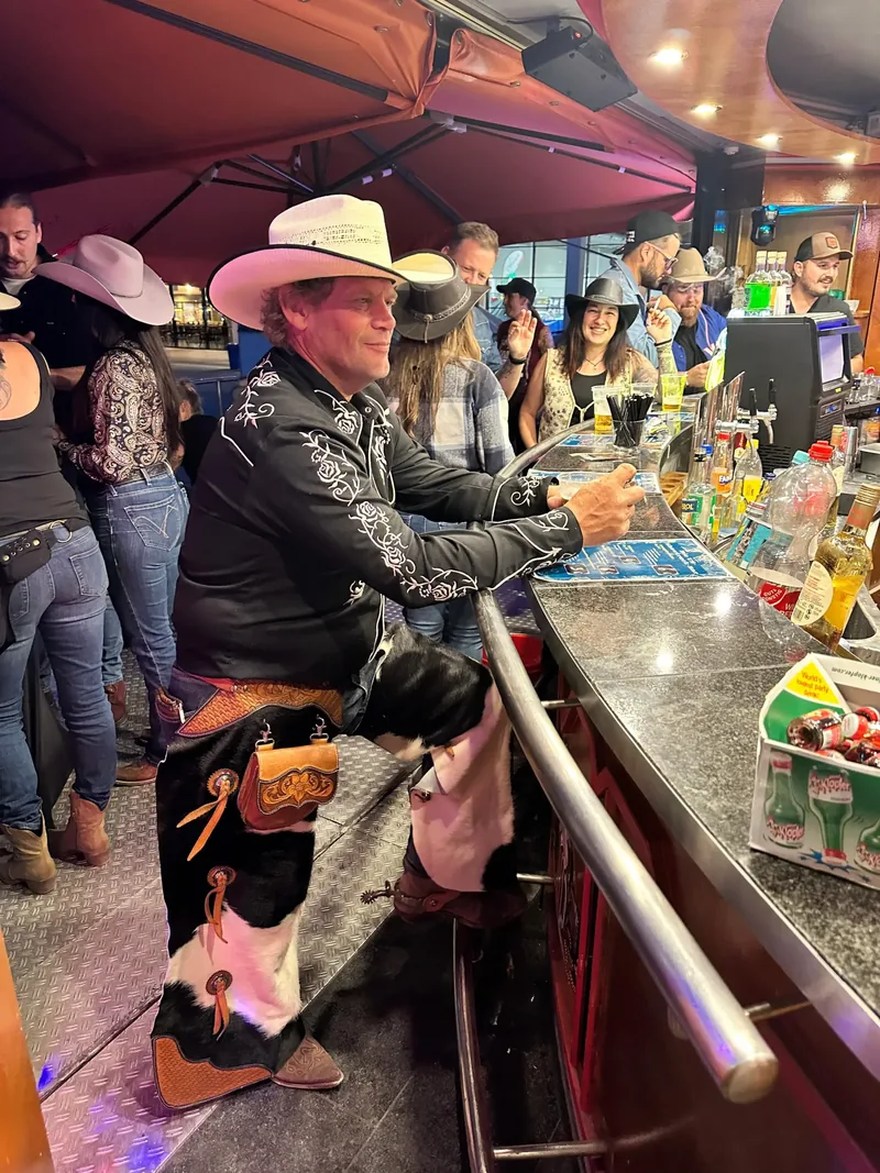 Gast mit Cowboyhut am mechanischen Bullen neben der Bar