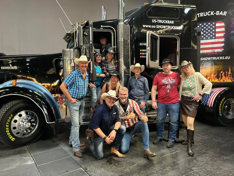 Besuchergruppe vor dem schwarzen Showtruck mit US-Flagge
